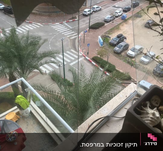 זכוכית מחוסמת שבורה על רצפת מרפסת לצד מעקה זכוכית